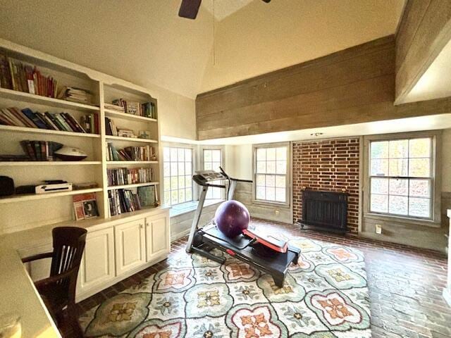 workout room featuring a fireplace, high vaulted ceiling, ceiling fan, and a healthy amount of sunlight