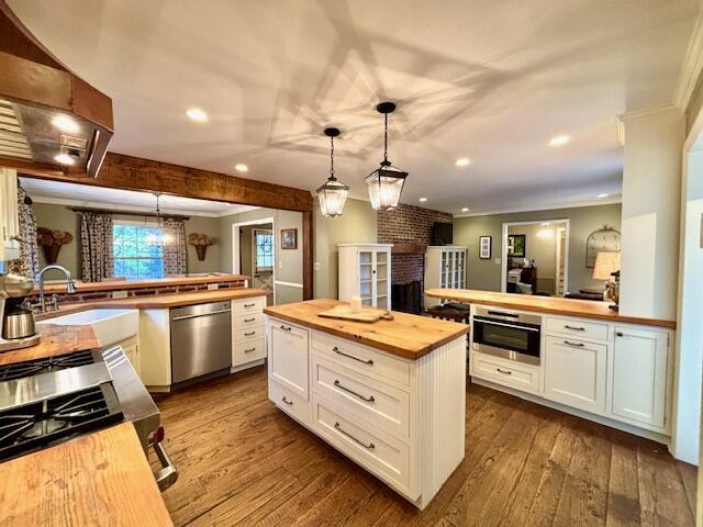 kitchen with wooden counters, appliances with stainless steel finishes, decorative light fixtures, and white cabinetry