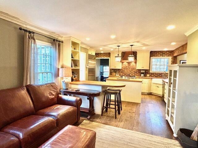 kitchen with a kitchen breakfast bar, dark hardwood / wood-style floors, premium range hood, kitchen peninsula, and decorative light fixtures