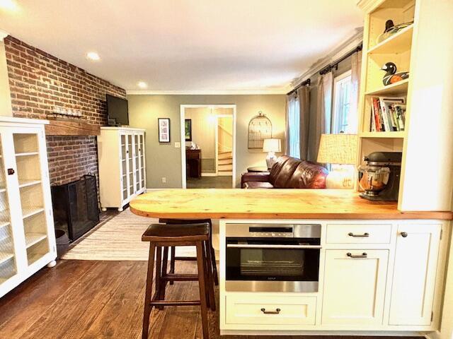 kitchen featuring wood counters, stainless steel oven, crown molding, and dark wood-type flooring