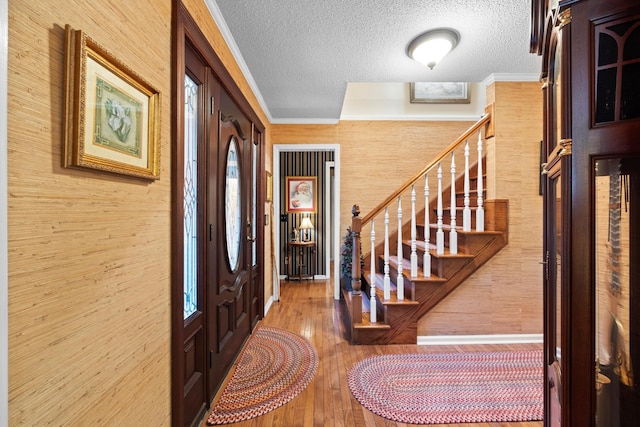 foyer entrance with wood walls, a textured ceiling, and hardwood / wood-style flooring