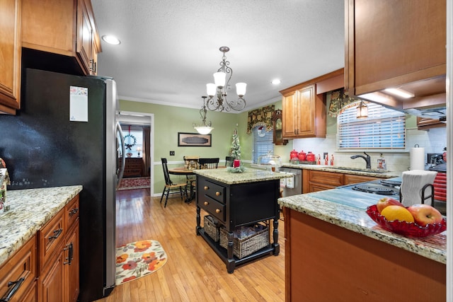 kitchen with appliances with stainless steel finishes, ornamental molding, a wealth of natural light, and light hardwood / wood-style flooring