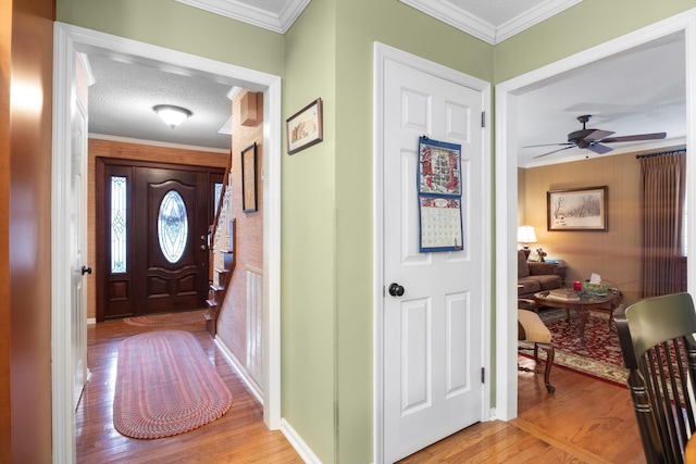 entrance foyer with a textured ceiling, light hardwood / wood-style flooring, ceiling fan, and ornamental molding