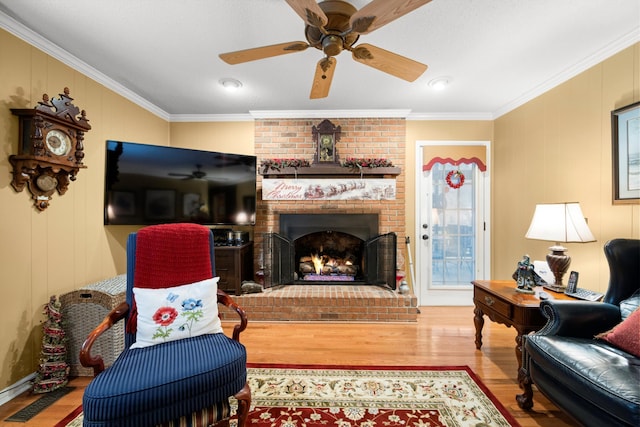 living room with a fireplace, hardwood / wood-style floors, ceiling fan, and ornamental molding