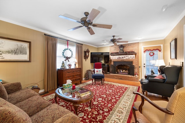 living room with a brick fireplace, ceiling fan, hardwood / wood-style floors, and ornamental molding