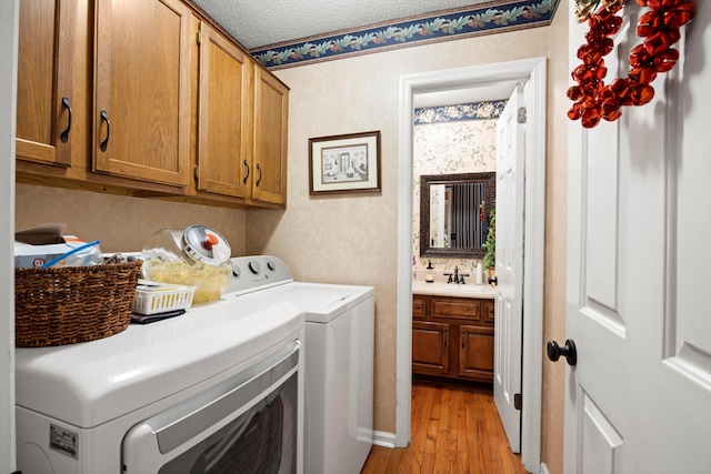 laundry area with sink, cabinets, a textured ceiling, washer and dryer, and light wood-type flooring