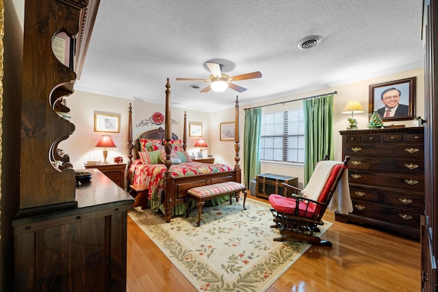 bedroom featuring a textured ceiling, light wood-type flooring, ceiling fan, and ornamental molding