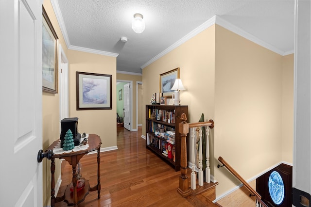 hallway featuring wood-type flooring, a textured ceiling, and ornamental molding