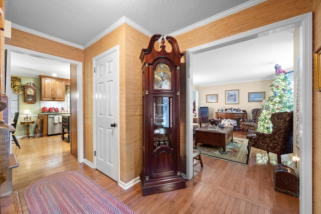 entrance foyer featuring light hardwood / wood-style floors, ornamental molding, and a textured ceiling