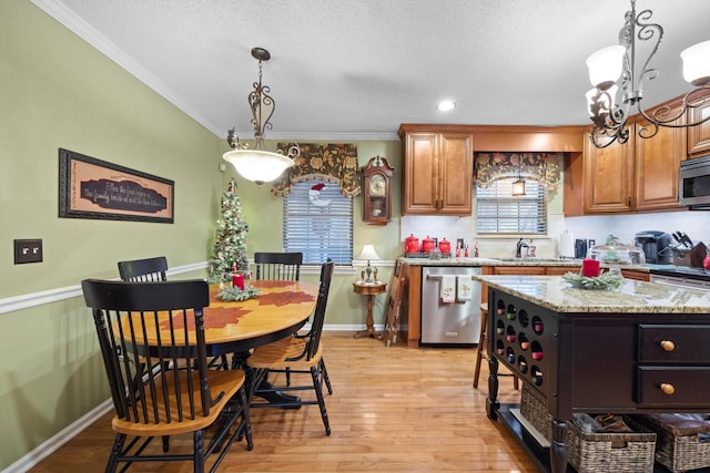 kitchen with light wood-type flooring, light stone counters, stainless steel appliances, crown molding, and a kitchen island