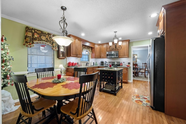 dining room with a textured ceiling, light hardwood / wood-style floors, an inviting chandelier, and crown molding