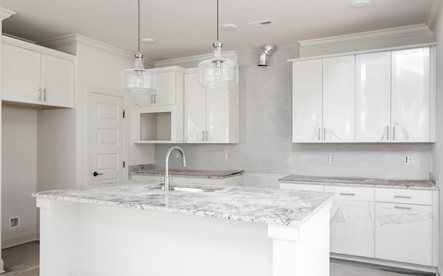 kitchen with decorative light fixtures, white cabinetry, and a center island with sink