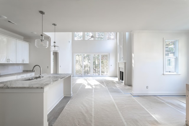 kitchen with white cabinets, light stone countertops, a wealth of natural light, and hanging light fixtures