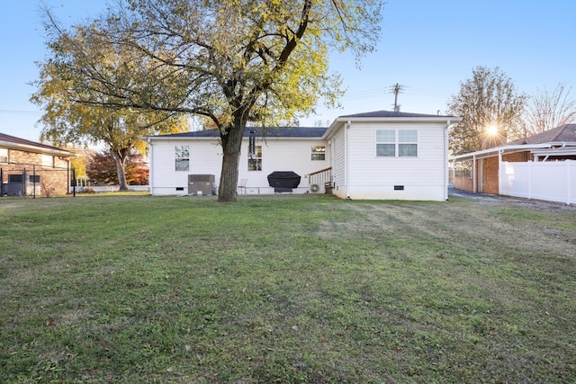 back of property featuring central air condition unit and a yard