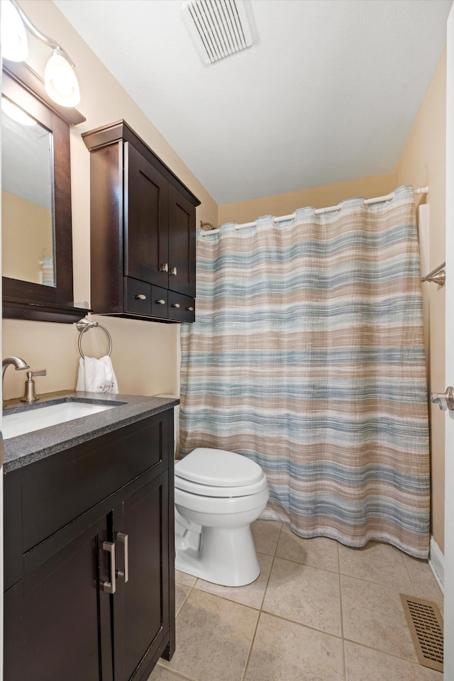 bathroom featuring tile patterned flooring, vanity, toilet, and walk in shower