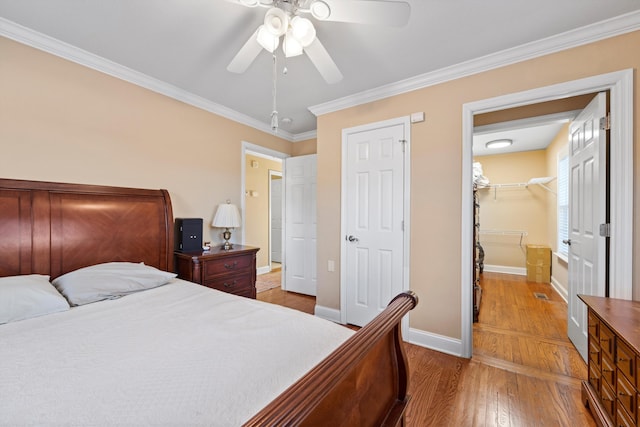 bedroom with ceiling fan, crown molding, hardwood / wood-style flooring, a spacious closet, and a closet