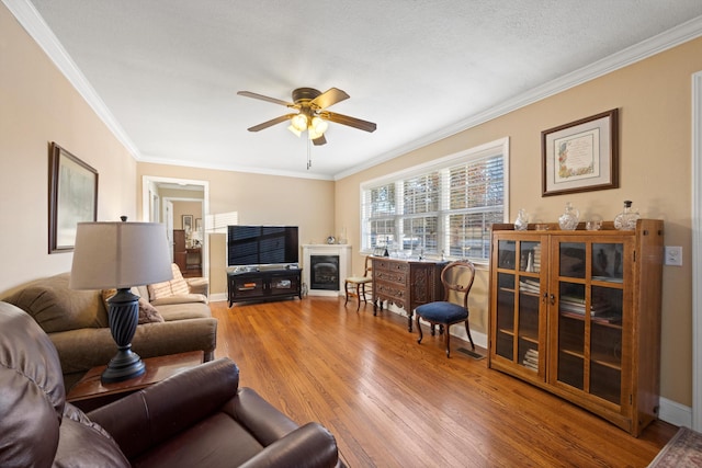 living room with hardwood / wood-style floors, a textured ceiling, ceiling fan, and ornamental molding