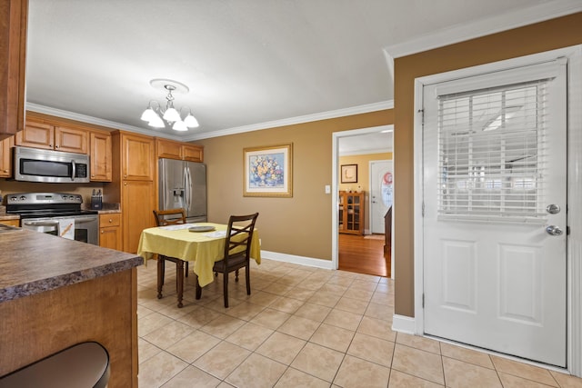 kitchen featuring appliances with stainless steel finishes, a chandelier, pendant lighting, light tile patterned floors, and ornamental molding