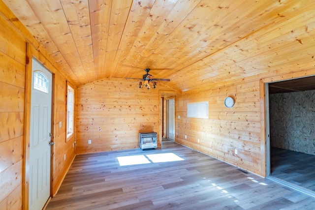 empty room featuring hardwood / wood-style floors, wood walls, vaulted ceiling, ceiling fan, and wood ceiling