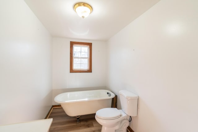 bathroom with hardwood / wood-style flooring, a washtub, and toilet