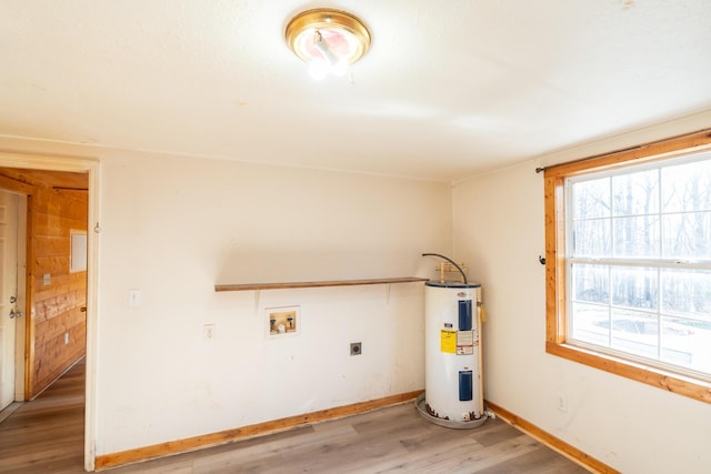 clothes washing area with hookup for an electric dryer, hookup for a washing machine, water heater, light hardwood / wood-style flooring, and wood walls