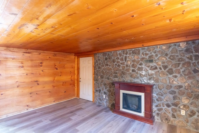 unfurnished living room with light wood-type flooring, wood walls, and wood ceiling