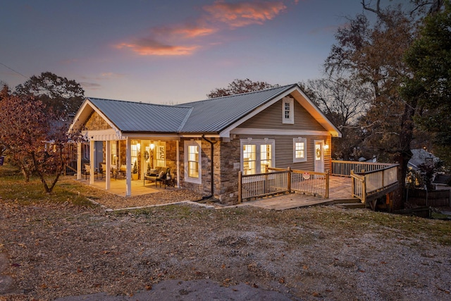 back house at dusk with a patio area and a deck