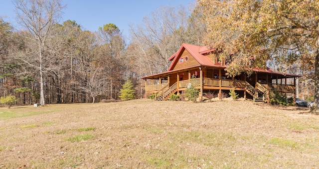 view of property exterior featuring a forest view, a yard, covered porch, stairs, and metal roof