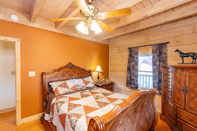 bedroom with wooden walls, baseboards, beamed ceiling, wooden ceiling, and wood finished floors