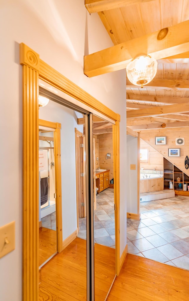 corridor with beamed ceiling, baseboards, wood ceiling, and wood finished floors