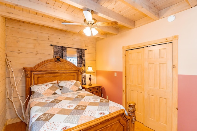 bedroom with beamed ceiling, wood walls, wooden ceiling, and light wood-style floors