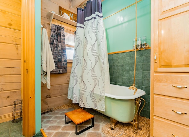 bathroom featuring tile walls and a freestanding tub