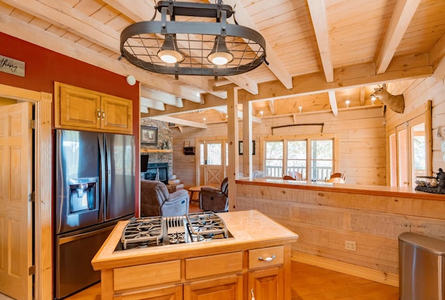 kitchen with wood ceiling, fridge with ice dispenser, wooden walls, and stainless steel gas stovetop