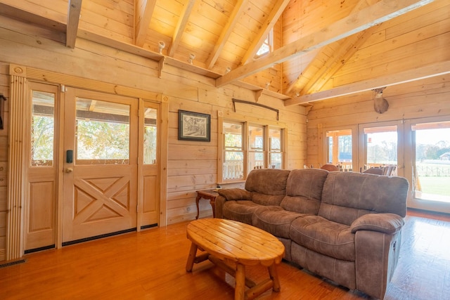 living room featuring wooden walls, wood finished floors, visible vents, beam ceiling, and wood ceiling