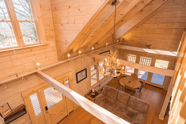 stairs with wood walls, wood ceiling, lofted ceiling with beams, a notable chandelier, and wood-type flooring