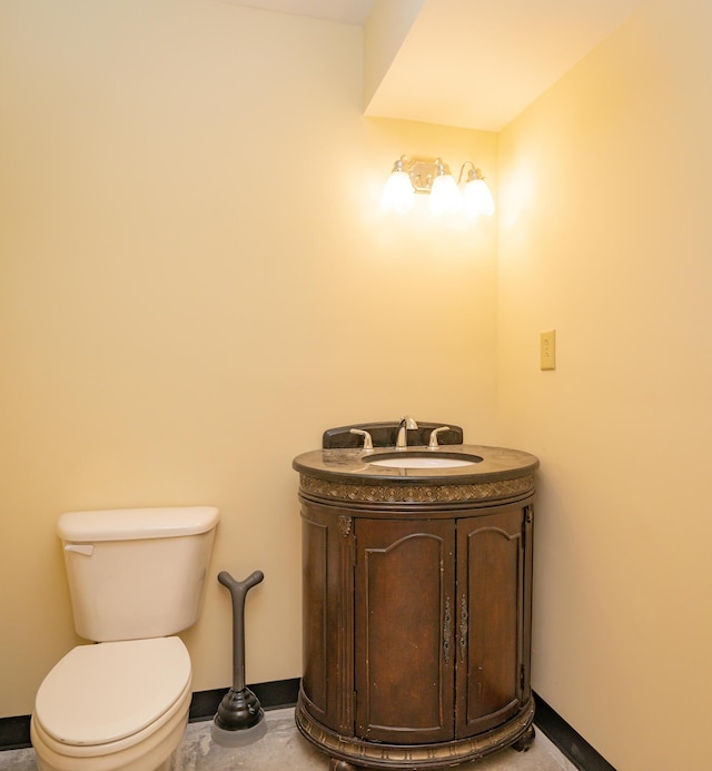 half bathroom featuring vanity, toilet, and baseboards