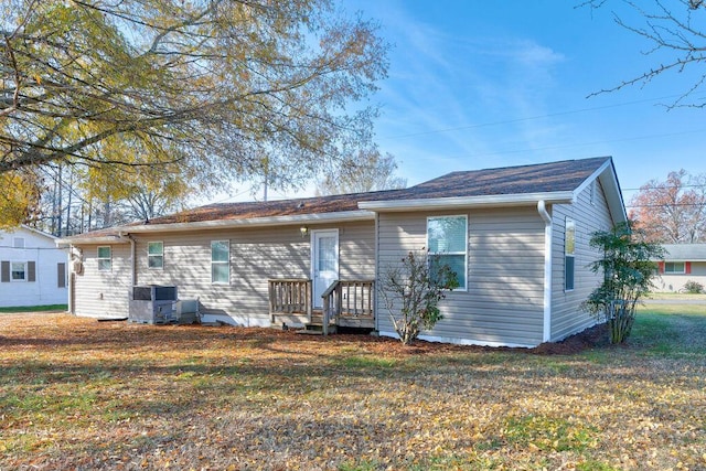 back of property featuring central air condition unit and a yard