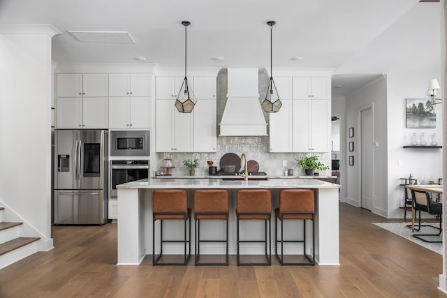 kitchen featuring stainless steel appliances, white cabinetry, a center island with sink, and custom exhaust hood