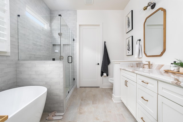 full bathroom featuring toilet, vanity, hardwood / wood-style flooring, and separate shower and tub