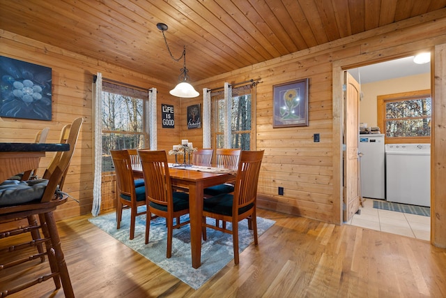 dining area featuring light wood-type flooring, wooden ceiling, and wood walls