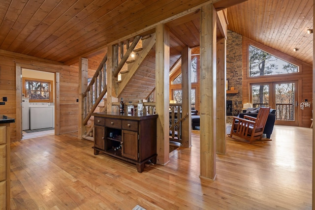 corridor featuring washer and clothes dryer, wood walls, wooden ceiling, high vaulted ceiling, and light hardwood / wood-style flooring