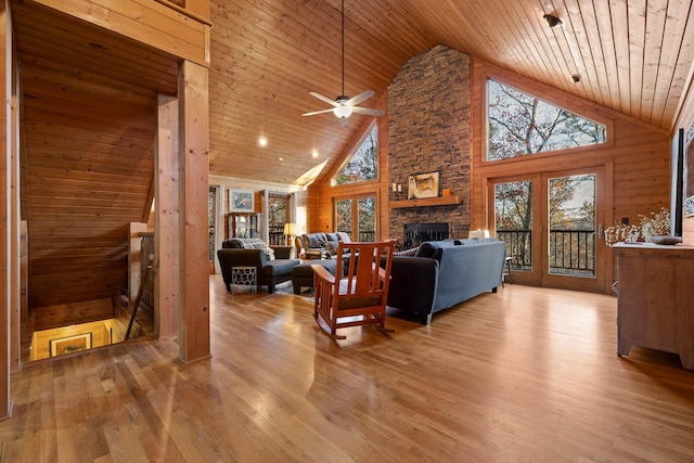 living room with light wood-type flooring, high vaulted ceiling, ceiling fan, and a healthy amount of sunlight