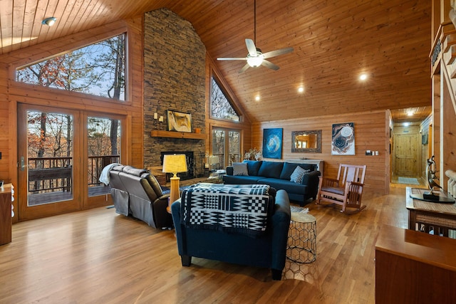 living room with wood walls, wooden ceiling, high vaulted ceiling, light hardwood / wood-style flooring, and ceiling fan