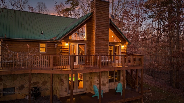 back house at dusk with french doors and a deck