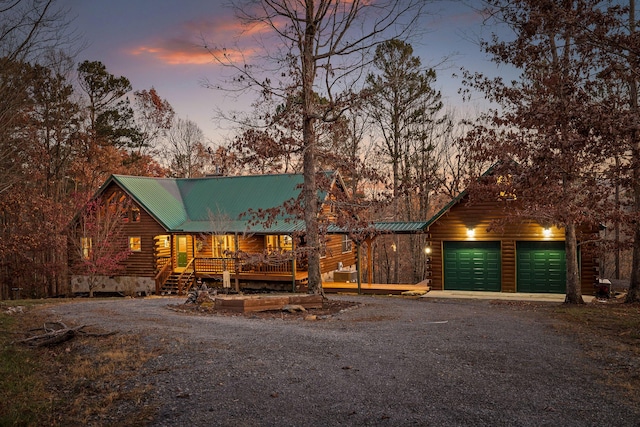 log-style house featuring a porch and a garage