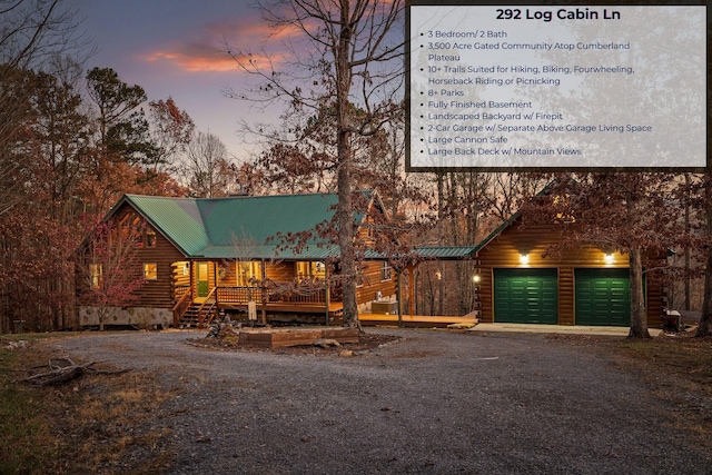view of front of home featuring driveway, a porch, log siding, and metal roof