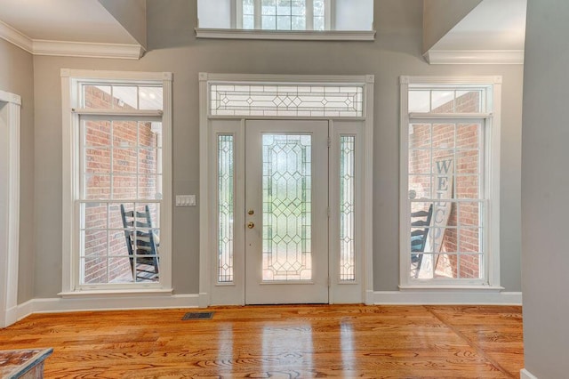 entryway with light hardwood / wood-style floors, crown molding, and a wealth of natural light