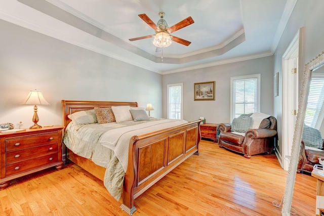 bedroom featuring ornamental molding, light hardwood / wood-style floors, ceiling fan, and a tray ceiling