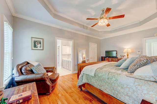 bedroom with a raised ceiling, ensuite bath, ceiling fan, ornamental molding, and light hardwood / wood-style floors