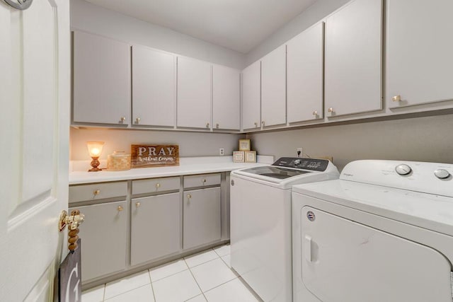 clothes washing area with separate washer and dryer, light tile patterned floors, and cabinets